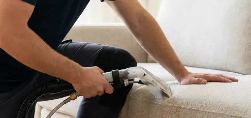 Professional upholstery cleaner deep-cleaning a fabric sofa with a handheld extraction tool, Pueblo, CO.